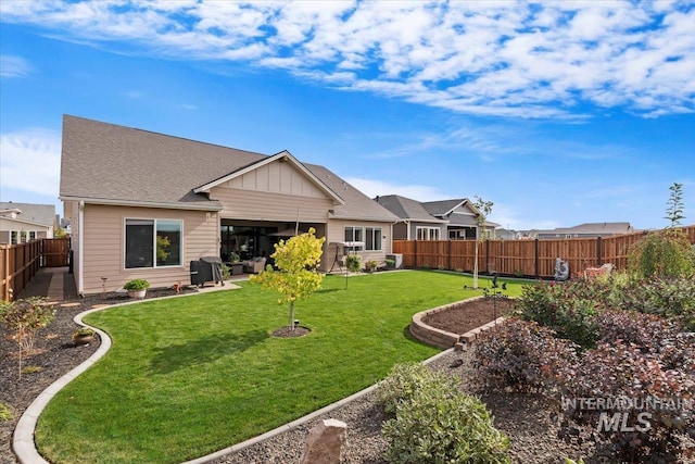 back of house with a patio, a lawn, board and batten siding, and a fenced backyard