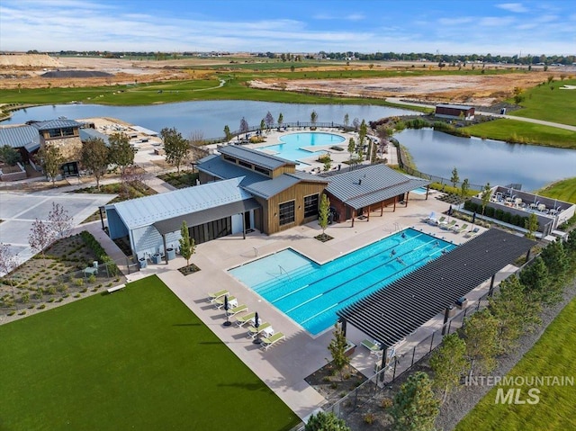 community pool with a patio area, a water view, and fence