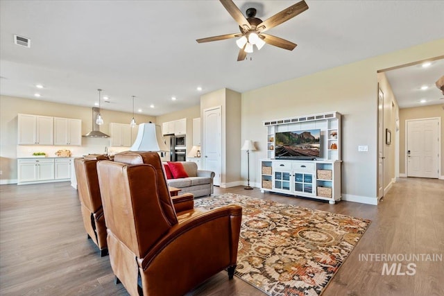 living room featuring recessed lighting, wood finished floors, visible vents, and baseboards