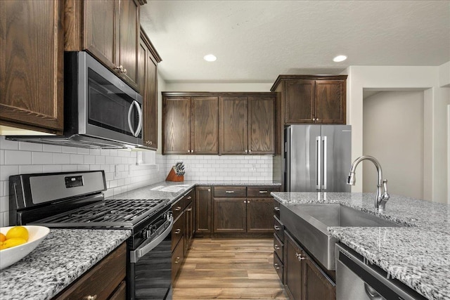 11638 W Quintale Dr, Nampa, ID 83686 - kitchen featuring appliances with stainless steel finishes, light wood-style flooring, light stone countertops, a sink, and recessed lighting