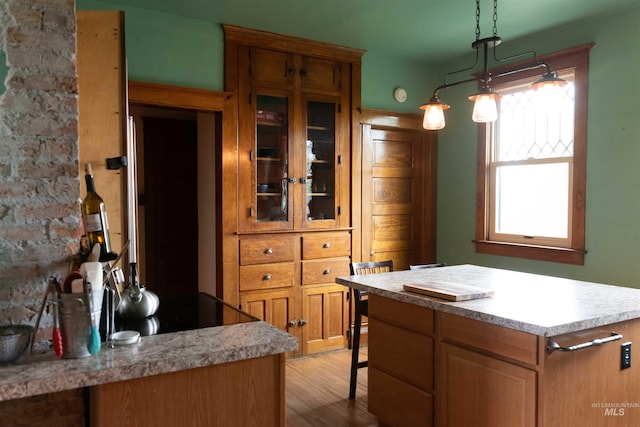 2771 S 850 E, Hagerman, ID 83332 - kitchen featuring light wood-style flooring, glass insert cabinets, light countertops, a center island, and decorative light fixtures