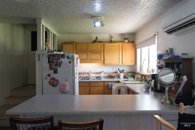 2771 S 850 E, Hagerman, ID 83332 - kitchen featuring freestanding refrigerator, a wall unit AC, a sink, a textured ceiling, and light countertops