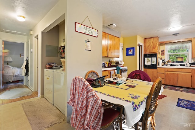 dining area featuring light tile patterned floors, independent washer and dryer, and a textured ceiling