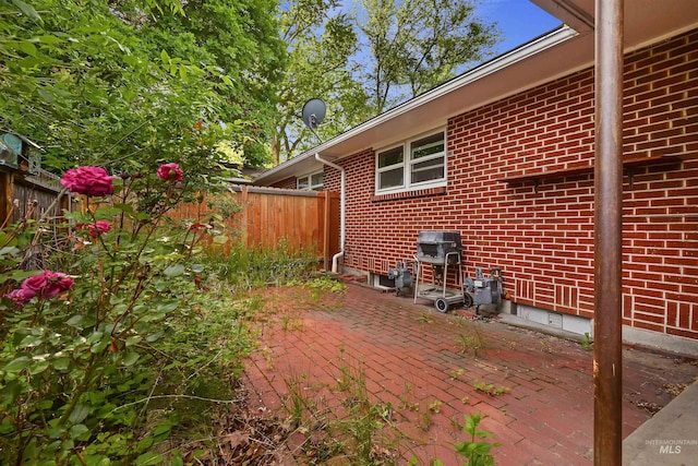view of home's exterior featuring brick siding, a fenced backyard, a patio, and crawl space