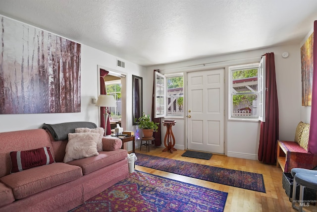 living room with baseboards, visible vents, a textured ceiling, and hardwood / wood-style floors