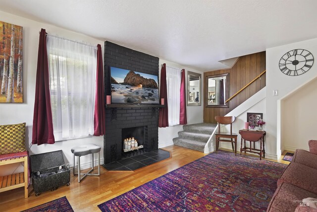 living area featuring a fireplace, baseboards, wood finished floors, and stairs