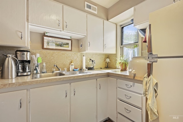 kitchen featuring a sink, freestanding refrigerator, light countertops, and visible vents
