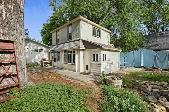 rear view of property featuring a patio area, fence, and stucco siding