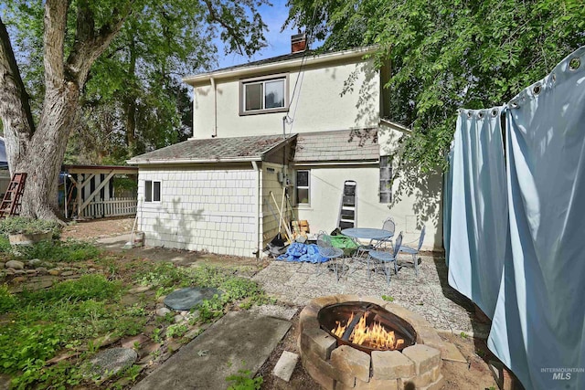 back of property featuring stucco siding, an outdoor fire pit, a patio area, fence, and a chimney