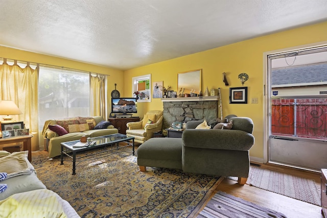 living area with a textured ceiling, wood finished floors, and a fireplace