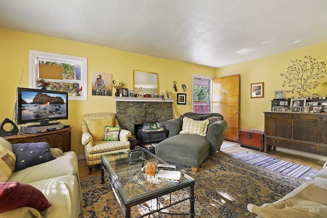 living room with a stone fireplace and wood finished floors