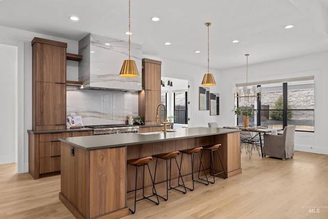 kitchen featuring dark countertops, wall chimney exhaust hood, modern cabinets, and a sink