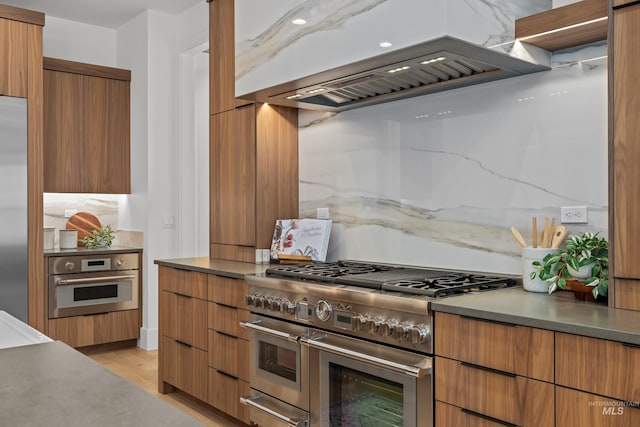 kitchen featuring range hood, high quality appliances, modern cabinets, and tasteful backsplash