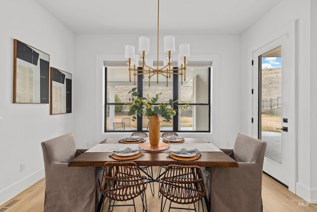 dining area with a notable chandelier, light wood-style flooring, baseboards, and visible vents