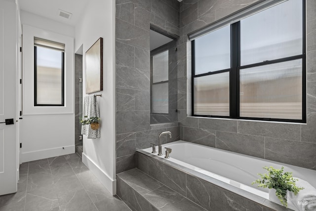 bathroom with a garden tub, visible vents, marble finish floor, and baseboards