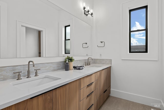 bathroom featuring double vanity, baseboards, and a sink