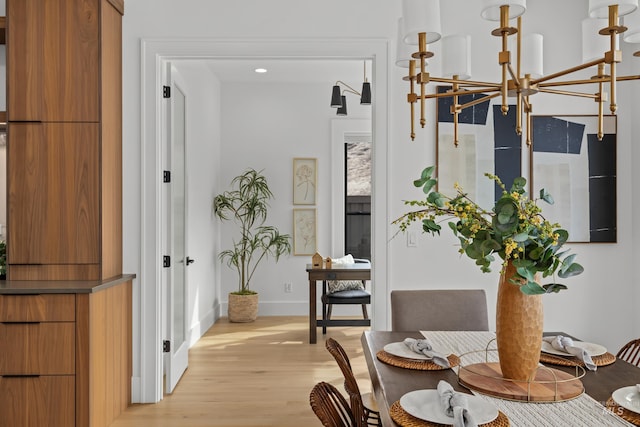 hallway featuring baseboards, an inviting chandelier, and light wood-style flooring