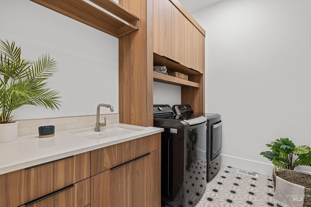 laundry room featuring visible vents, a sink, baseboards, cabinet space, and separate washer and dryer