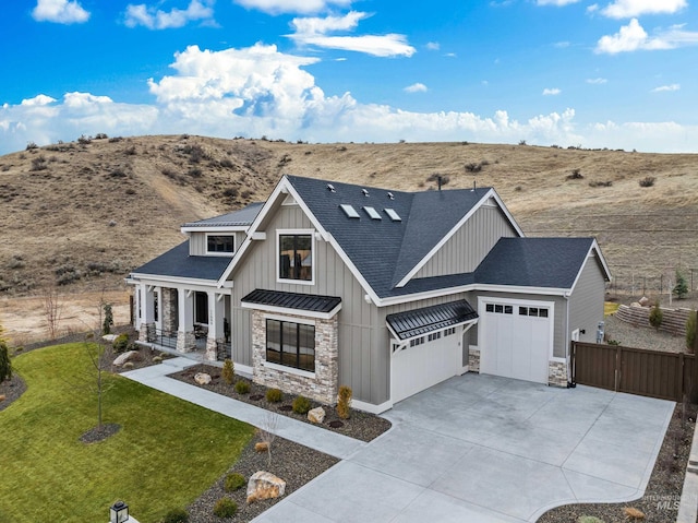 view of front of property featuring board and batten siding, concrete driveway, a front yard, a garage, and stone siding