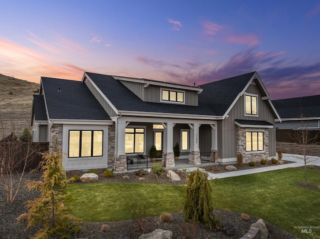 view of front of house featuring a yard, stone siding, board and batten siding, and a shingled roof