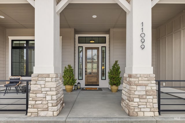 doorway to property featuring stone siding and a porch