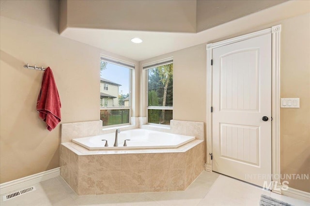 bathroom with tile patterned floors and tiled bath