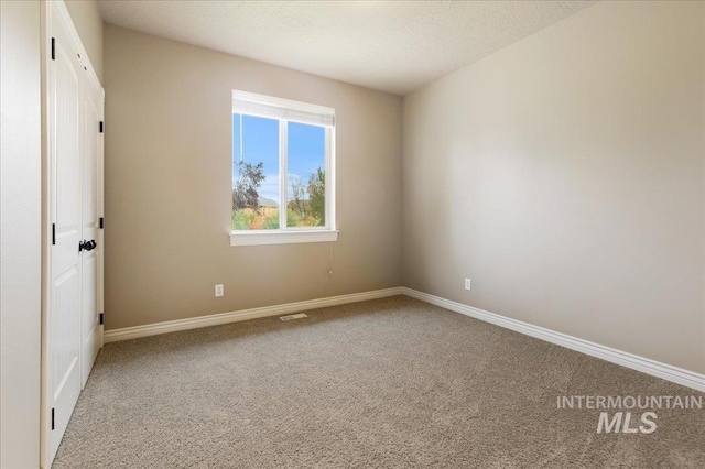 empty room with carpet floors and a textured ceiling