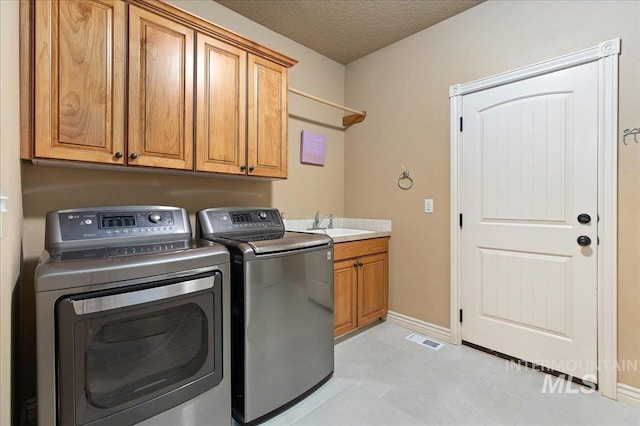 clothes washing area featuring cabinets, light tile patterned floors, independent washer and dryer, and a textured ceiling