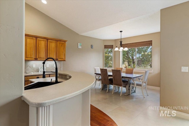 kitchen featuring lofted ceiling, hanging light fixtures, light tile patterned flooring, decorative backsplash, and a chandelier