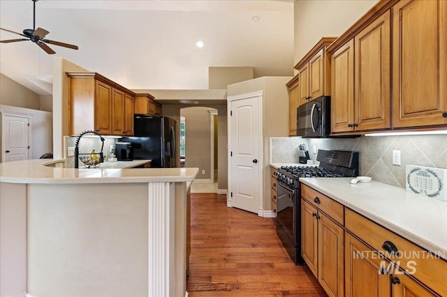 kitchen featuring backsplash, lofted ceiling, and black appliances