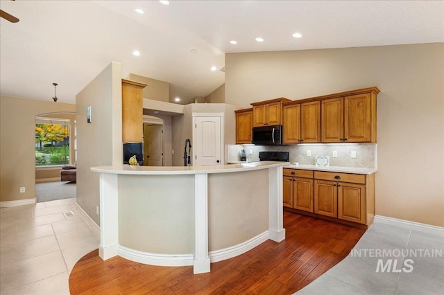 kitchen with range, tile patterned flooring, high vaulted ceiling, decorative backsplash, and kitchen peninsula