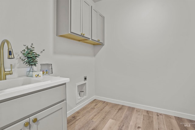 clothes washing area featuring light hardwood / wood-style flooring, cabinets, washer hookup, electric dryer hookup, and sink