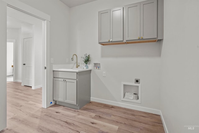 washroom featuring cabinets, washer hookup, electric dryer hookup, sink, and light wood-type flooring