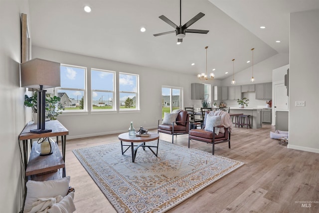 living room featuring high vaulted ceiling, ceiling fan with notable chandelier, and light wood-type flooring