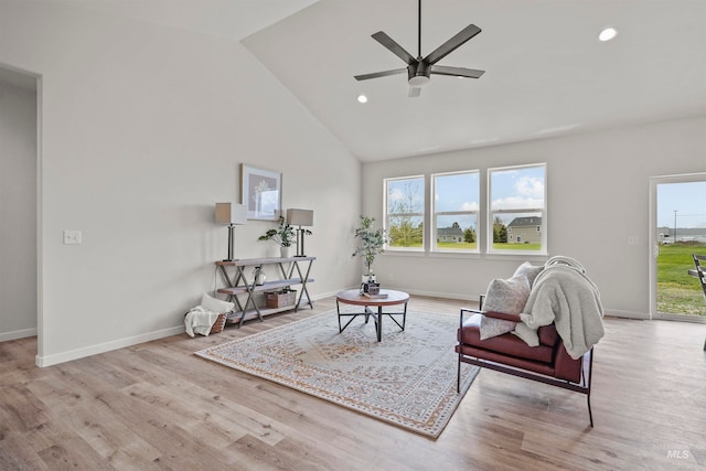 living area featuring high vaulted ceiling, light hardwood / wood-style floors, ceiling fan, and plenty of natural light