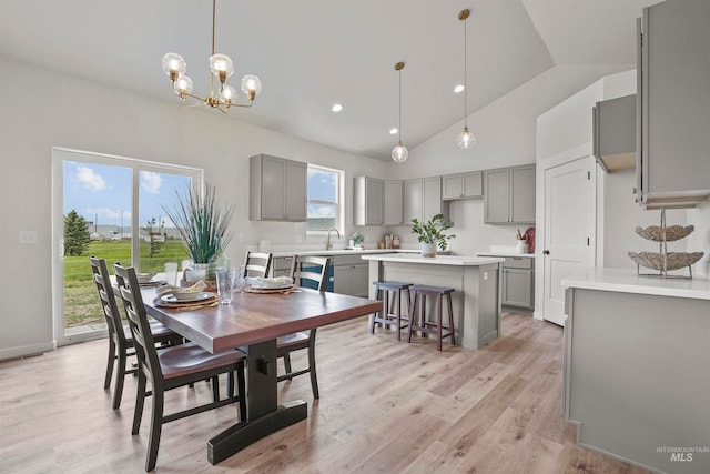 dining space with sink, high vaulted ceiling, a notable chandelier, and light wood-type flooring