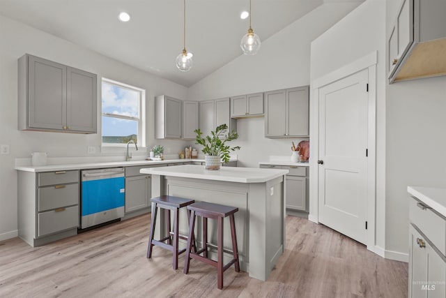 kitchen featuring pendant lighting, light wood-type flooring, vaulted ceiling, a kitchen island, and dishwasher