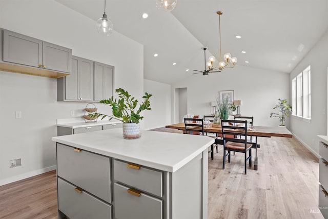 kitchen featuring a kitchen island, light hardwood / wood-style flooring, lofted ceiling, gray cabinetry, and pendant lighting