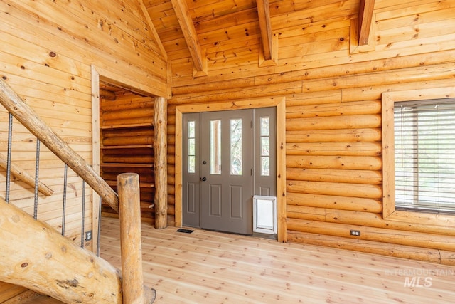 foyer entrance with wood ceiling, beamed ceiling, light wood-type flooring, and rustic walls