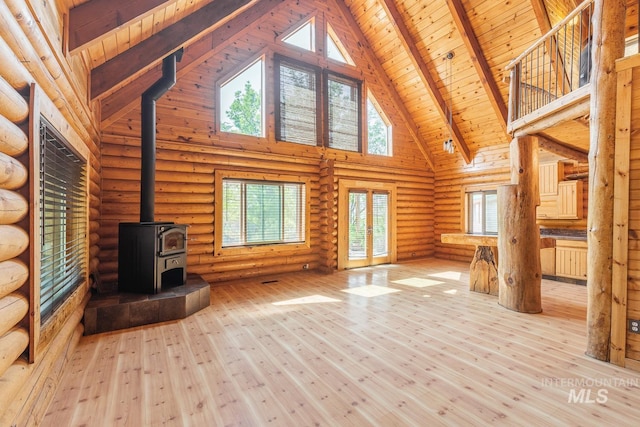 unfurnished living room with a wood stove, light hardwood / wood-style floors, rustic walls, high vaulted ceiling, and wooden ceiling