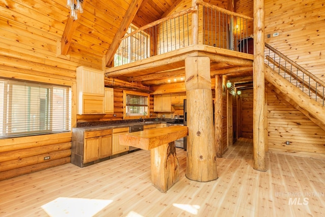 kitchen with light hardwood / wood-style flooring, log walls, appliances with stainless steel finishes, wooden ceiling, and high vaulted ceiling