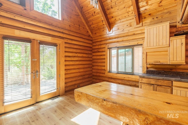 kitchen with high vaulted ceiling, light wood-style flooring, wood ceiling, french doors, and rustic walls