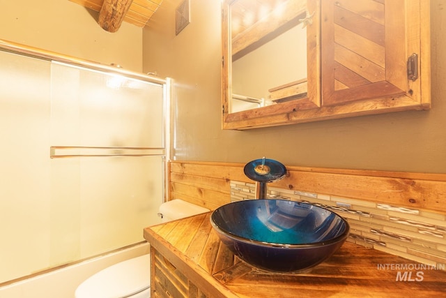 bathroom featuring toilet, wood walls, vanity, and visible vents