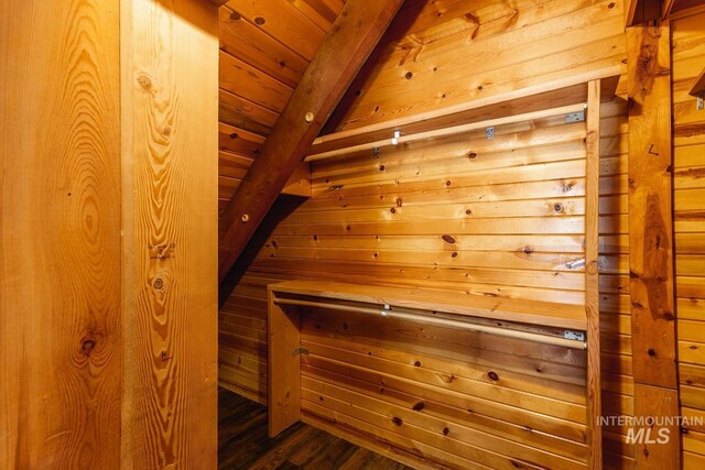 interior space with beam ceiling, wooden ceiling, wood walls, and a sauna