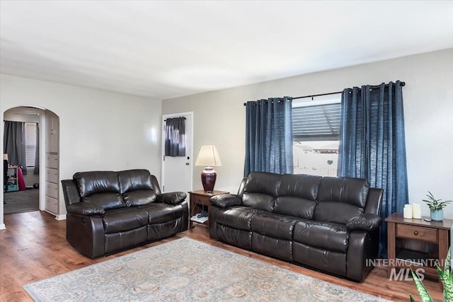 living room with arched walkways and wood finished floors