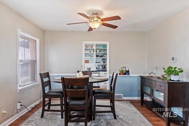 dining area featuring wood finished floors, baseboards, and ceiling fan