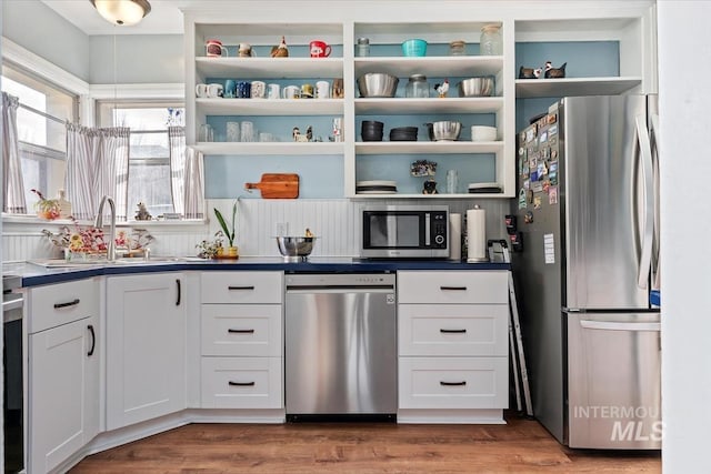 kitchen featuring open shelves, white cabinets, wood finished floors, and stainless steel appliances