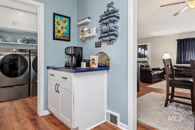 laundry room featuring visible vents, independent washer and dryer, a ceiling fan, wood finished floors, and laundry area