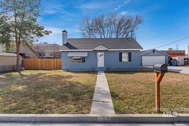 view of front of property with an outbuilding, fence, a front yard, a shingled roof, and a chimney