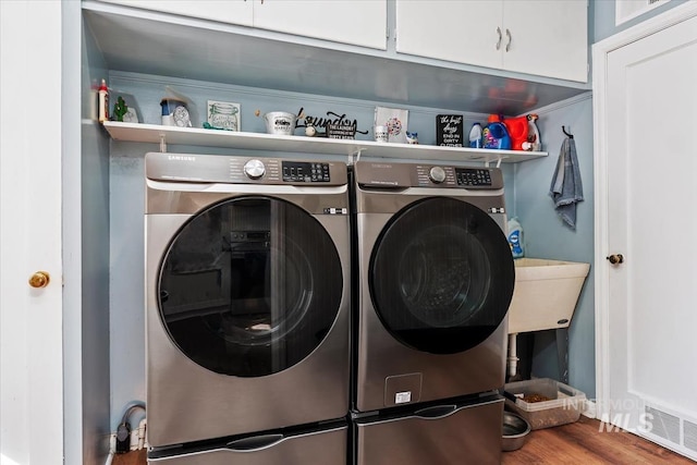 washroom with cabinet space, wood finished floors, and separate washer and dryer